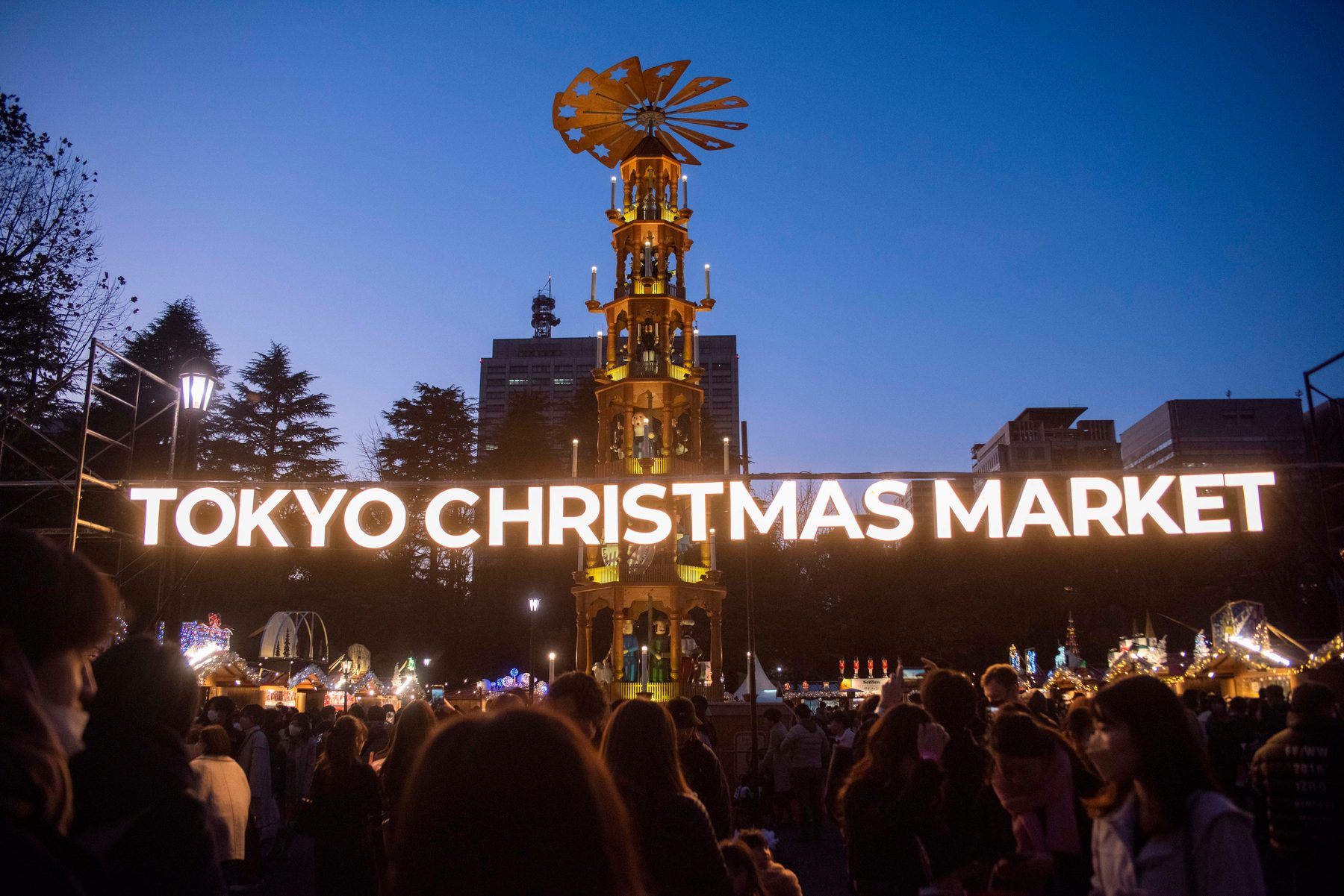 夕暮れの会場に輝くTOKYO CHRISTMAS MARKETのサインとクリスマスピラミッド